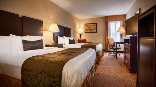 een hotelkamer met 2 bedden en een bureau bij Best Western Plus Edison Inn in Garner