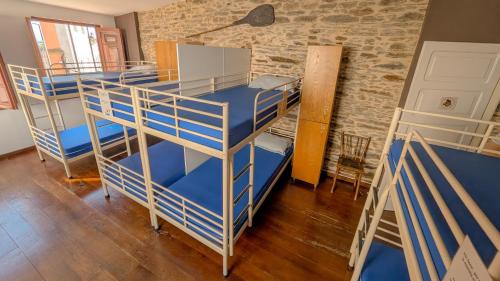 a room with three bunk beds and a brick wall at Albergue Mayor in Sarria