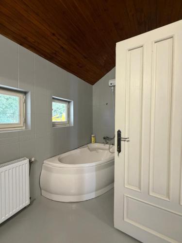 a white bathroom with a tub and a window at Hotel Turist Beharca in Beharca