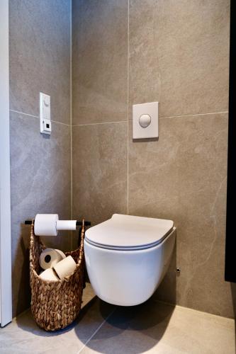 a bathroom with a toilet and a basket of toilet paper at Modern house secluded in nature in Storbukt