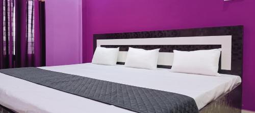a bedroom with a large bed with purple walls at Saraswati Sadan Homestay Ayodhya in Faizābād