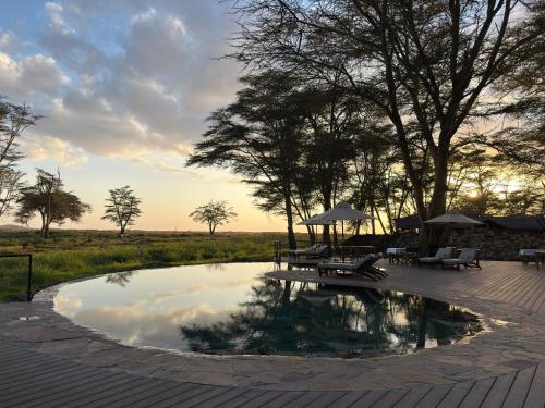 a pool of water with a picnic table and benches at Soroi Amboseli in Amboseli