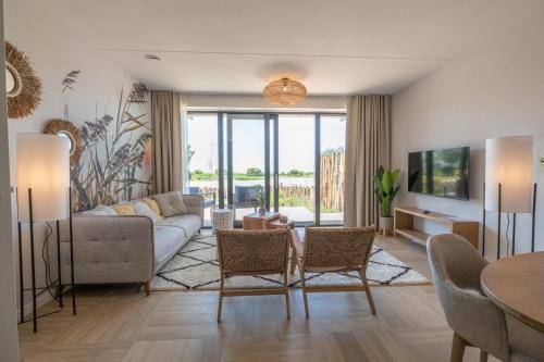 a living room with a couch and a table and chairs at MarinaPark Beach Resort Soal - Wellness Apartments in Workum