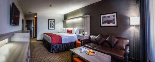 a hotel room with a bed and a couch at Best Western Plus Village Park Inn in Calgary