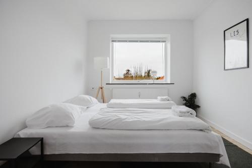a white bedroom with a large bed and a window at Lovely cozy apartment in Søborg
