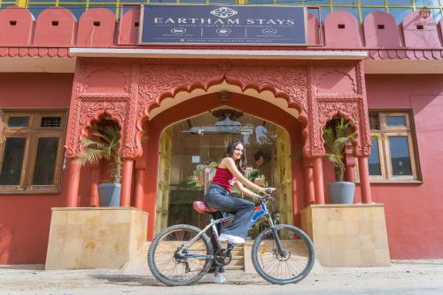 a woman riding a bike in front of a store at Eartham Stays, Pushkar in Pushkar