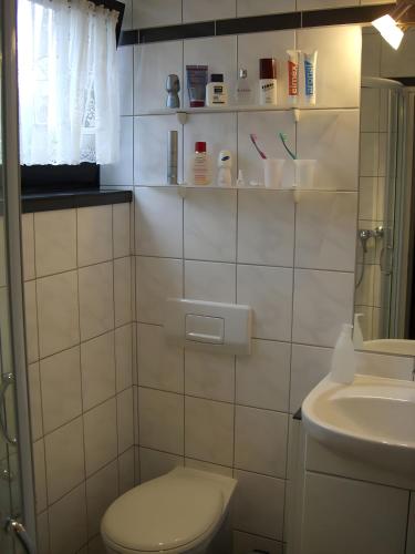 a white bathroom with a toilet and a sink at Nordseeferienbungalow in Butjadingen