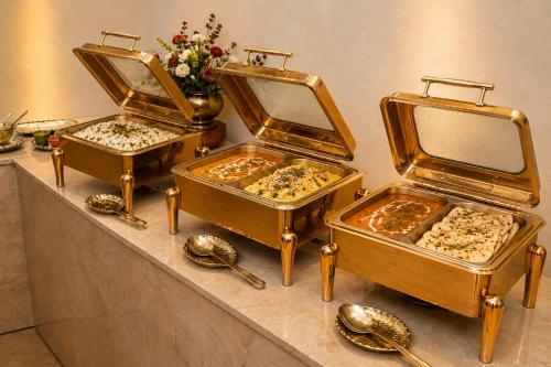 three trays of food sitting on a counter with spoons at Street Studio by Lime Tree Hotel Sector 51 Gurgaon in Gurgaon