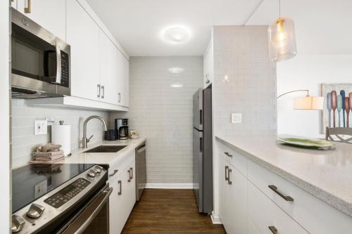 a kitchen with white cabinets and a black refrigerator at SUGAR BEACH RESORT, #421 in Kihei