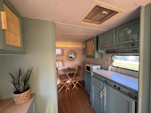 an rv kitchen with blue cabinets and a table at Caravana Lobo Camp in Boca de Huérgano