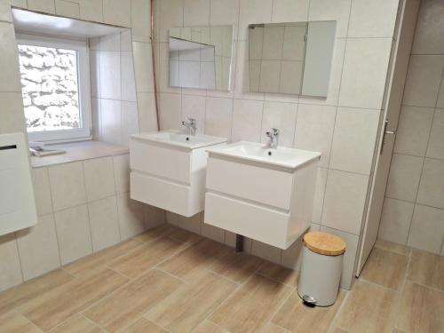 a bathroom with two sinks and a trash can at La belle étoile in Saugues