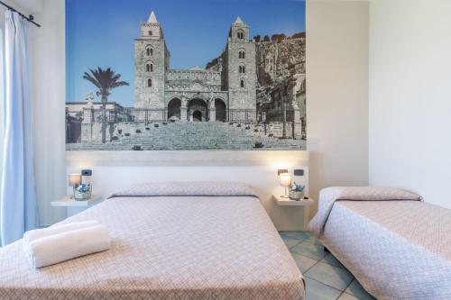 zwei Betten in einem Zimmer mit einem Bild einer Kirche in der Unterkunft Hotel Tourist in Cefalú