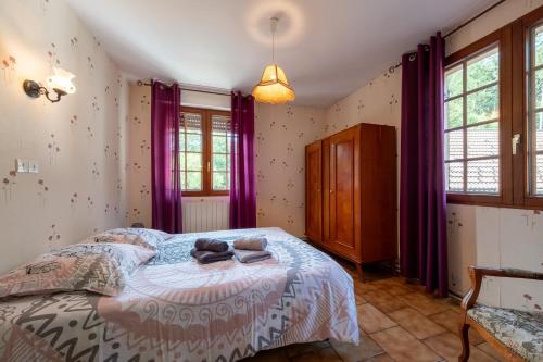 a bedroom with a bed with purple curtains at La Petite Caille - Appartement 10 in Plombières-les-Bains