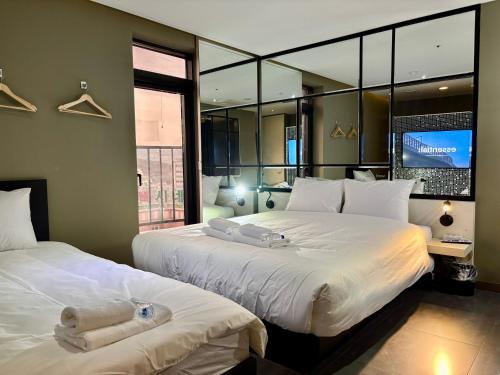 two beds in a room with a large window at HERTZ Hotel in Seoul