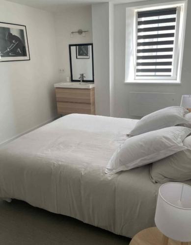 a white bedroom with a large bed and a window at appartement la pause coté mer in Santec