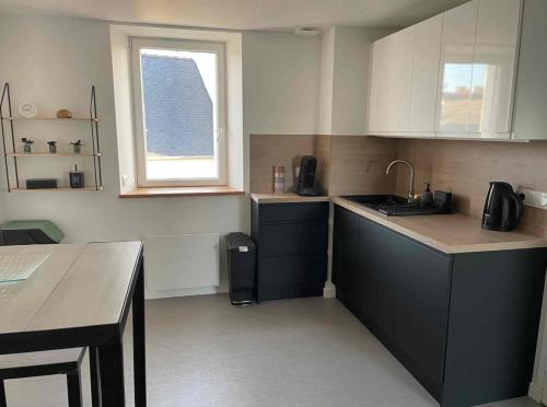 a kitchen with white cabinets and a sink and a window at appartement la pause coté mer in Santec
