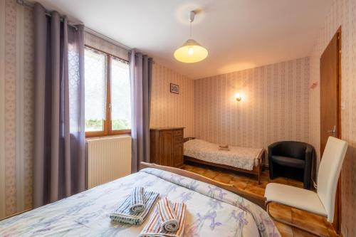 a bedroom with a bed and a chair and a window at Appartement 5 - La Petite Caille in Plombières-les-Bains