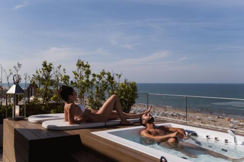 a couple of women sitting in a pool with a dog at Hotel Sporting Riccione in Riccione
