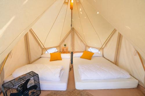two beds in a triangular tent with yellow pillows at Kampaoh El Palmar in El Palmar