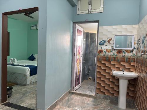 a bathroom with a sink and a shower and a bed at Das & Das Hotel in Bhubaneshwar