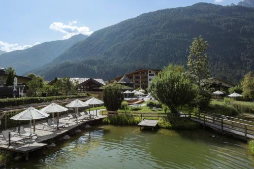 a resort with tables and umbrellas in a lake at VAYA Lechtal in Elbigenalp