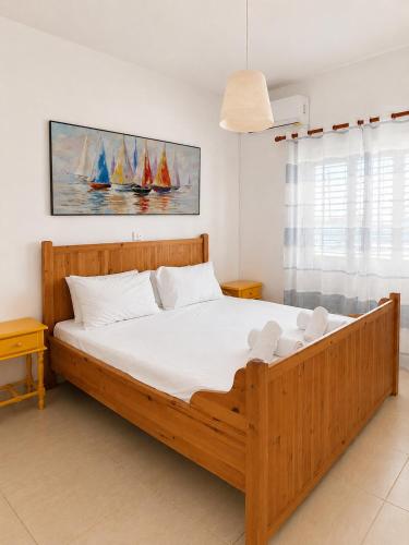 a bedroom with a wooden bed with sailboats on the wall at Andromeda Apartment in Polis Chrysochous