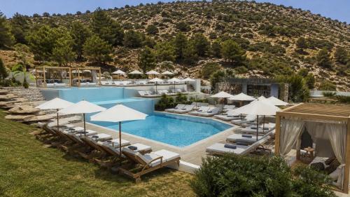 an outdoor swimming pool with lounge chairs and umbrellas at Stella View in Pefki