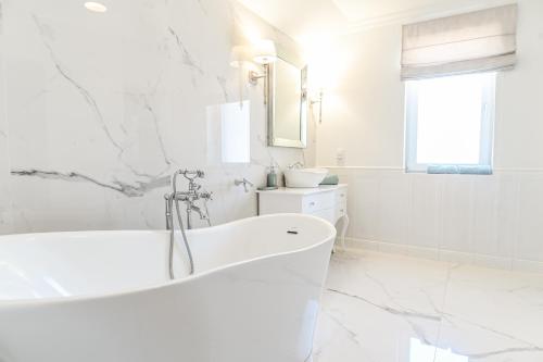 a white bathroom with a tub and a sink at Villa Laurent in Charzykowy