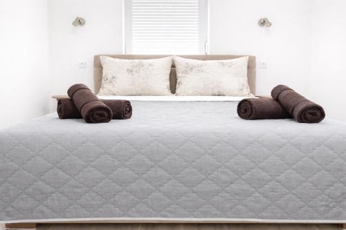 a white bed with brown pillows on top of it at Lotus house in Zrenjanin