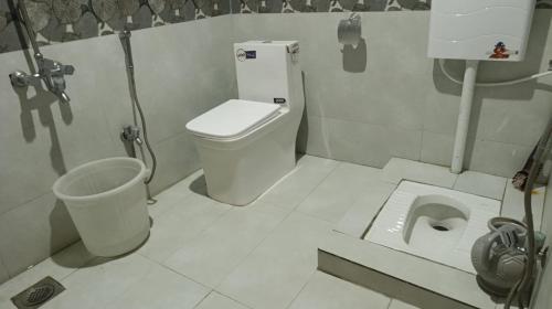 a white bathroom with a toilet and a sink at Royal Palace in Naran