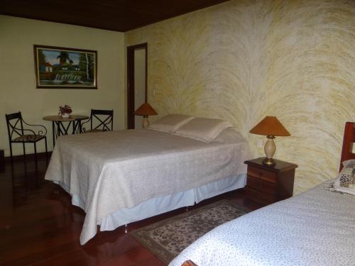 1 dormitorio con 1 cama y 2 mesas con lámparas en Pousada da Mantiqueira, en Visconde De Maua
