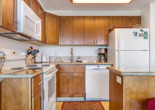 a kitchen with wooden cabinets and white appliances at KIHEI SURFSIDE #109 in Wailea