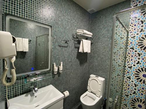 a bathroom with a sink and a toilet and a mirror at Orda Hotel in Yunusobod