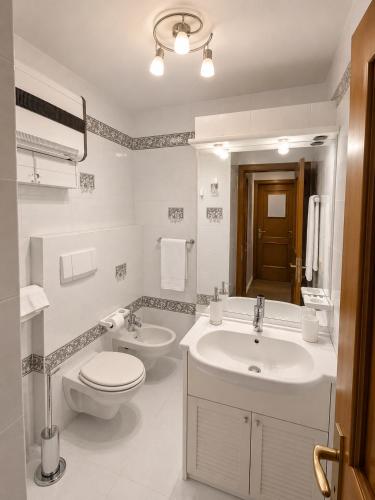 a white bathroom with a toilet and a sink at Appartamento Cuore by AMA Val di Fassa in Campitello di Fassa