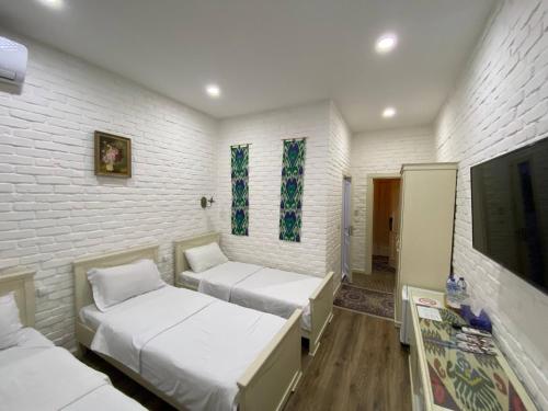a room with two beds and a tv at Orda Hotel in Yunusobod