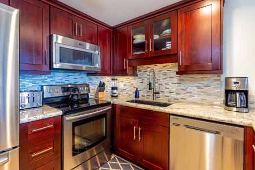 a kitchen with wooden cabinets and stainless steel appliances at Hale Mahina #B-405 in Honokowai