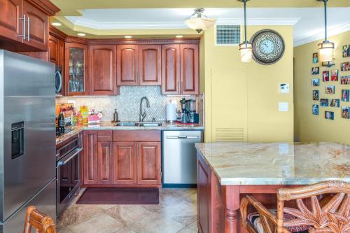 a kitchen with wooden cabinets and a stainless steel refrigerator at SUGAR BEACH RESORT, #131 in Kihei