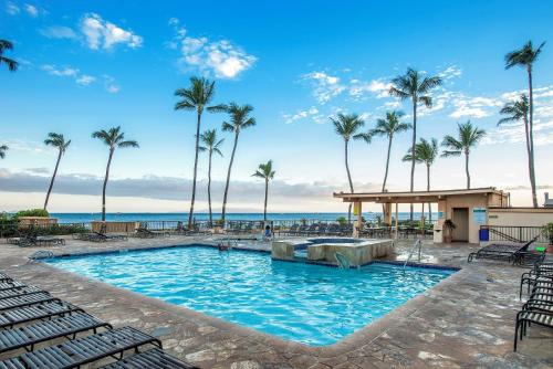 a swimming pool with palm trees and the ocean at SUGAR BEACH RESORT, #235 in Kihei