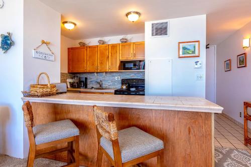 a kitchen with a counter with two chairs and a refrigerator at SUGAR BEACH RESORT #227 in Kihei
