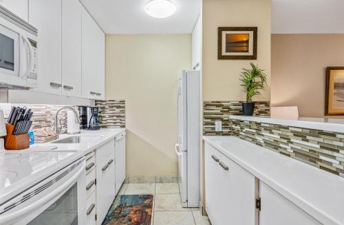 a kitchen with white cabinets and a refrigerator at SUGAR BEACH RESORT #125 in Kihei