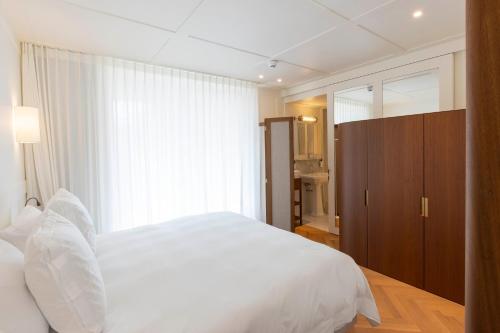 a bedroom with a white bed and a large window at Hotel Montaigne in Ostend