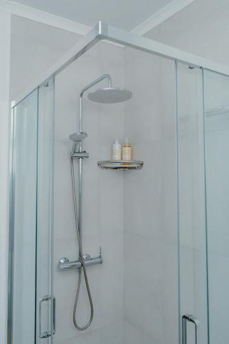a shower with a shower head in a bathroom at Kalumi Aparthotels - Japandi-Style Apartments with Terrace, Pergola, and Portuguese BBQ in Vila Nova de Milfontes