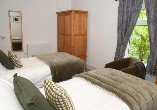 a bedroom with two beds and a dresser and a window at Gwesty Seren Hotel in Blaenau-Ffestiniog
