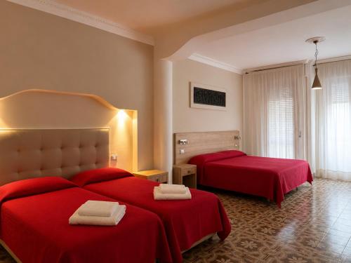 a hotel room with two beds with red sheets at Hotel Cristallo - Chianciano Terme in Chianciano Terme