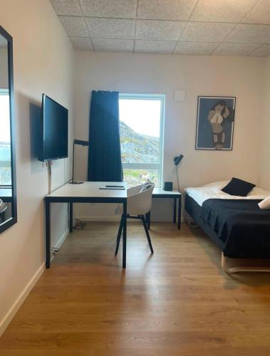 a bedroom with a desk and a bed and a window at Tuukkaq Apartments in Nuuk