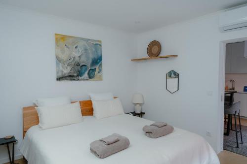a bedroom with a white bed with towels on it at Kalumi Aparthotels - Japandi-Style Apartments with Terrace, Pergola, and Portuguese BBQ in Vila Nova de Milfontes
