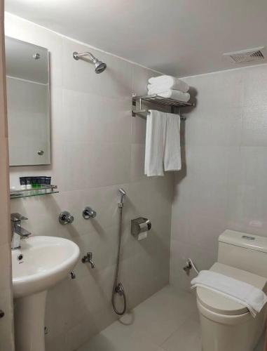 a white bathroom with a toilet and a sink at Kazi Castle Rajshahi in Rājshāhi