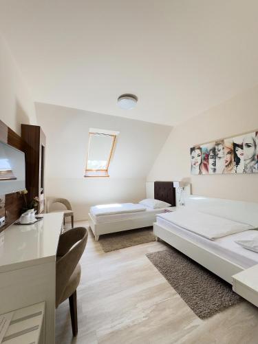 a white room with two beds and a desk at Mizse Motel in Lajosmizse