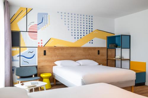 a bedroom with two beds and a wall mural at ibis Styles Angouleme Centre in Angoulême