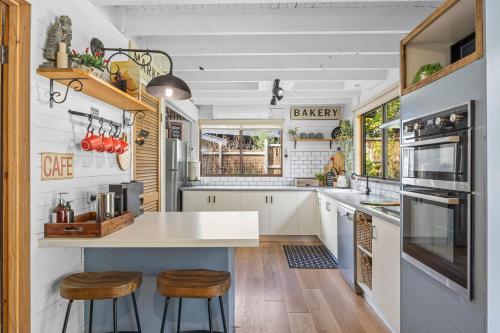 a kitchen with a large white counter and stools at Cedar Country Retreat in Halls Gap